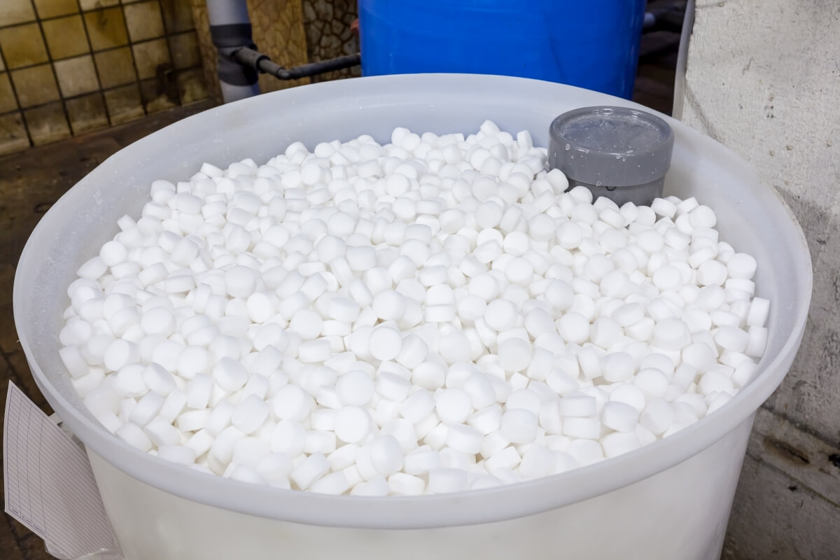 Duże pojemnik pełen białych tabletek do zmiękczania wody.